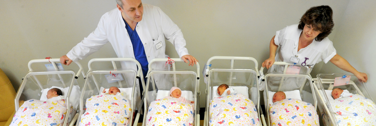 Ein Arzt und eine Krankenschwester hinter zwei Reihen Betten mit Babys in der Neugeborenenstation in einem Krankenhaus in Halle © picture alliance/ZB/Waltraud Grubitzsch Ein Arzt und eine Krankenschwester hinter zwei Reihen Betten mit Babys in der Neugeborenenstation in einem Krankenhaus in Halle © picture alliance/ZB/Waltraud Grubitzsch