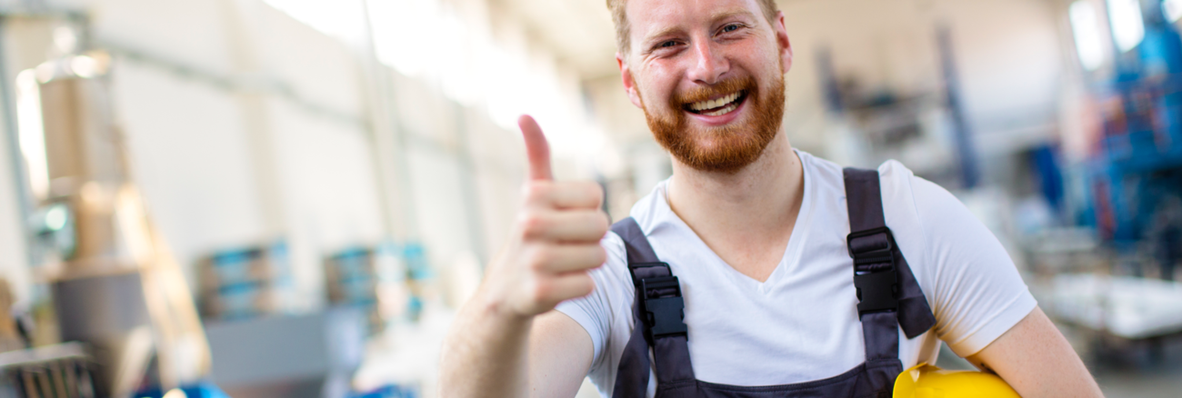 Ein Arbeiter mit gelbem Helm unter seinem linken Arm hebt zustimmend den rechten Daumen © iStock/milanvirijevic Ein Arbeiter mit gelbem Helm unter seinem linken Arm hebt zustimmend den rechten Daumen © iStock/milanvirijevic