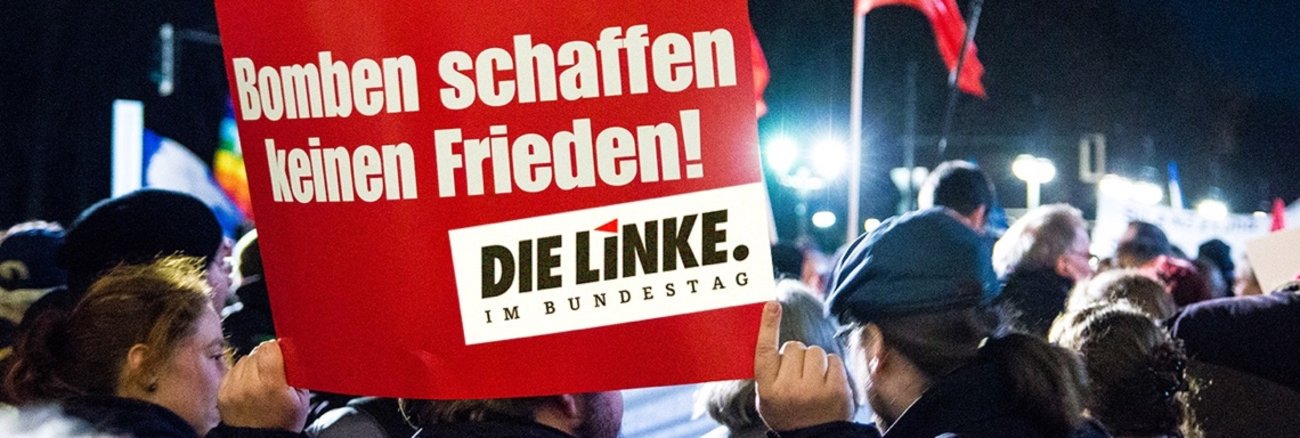 Teilnehmer an einer Friedenskundgebung halten ein Schild mit Aufschrift: Bomben schaffen keinen Frieden! Teilnehmer an einer Friedenskundgebung halten ein Schild mit Aufschrift: Bomben schaffen keinen Frieden!