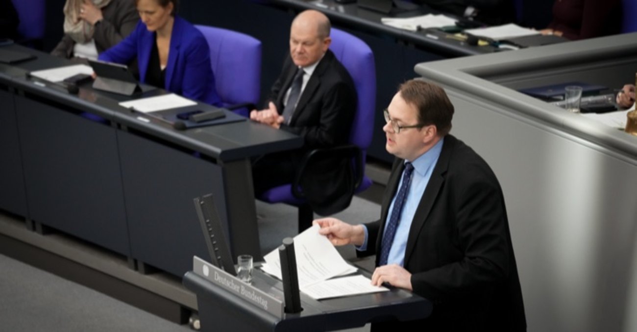 Sören Pellmann am Rednerpult des Bundestages, dahinter Bundeskanzler Olaf Scholz auf der Regierungsbank