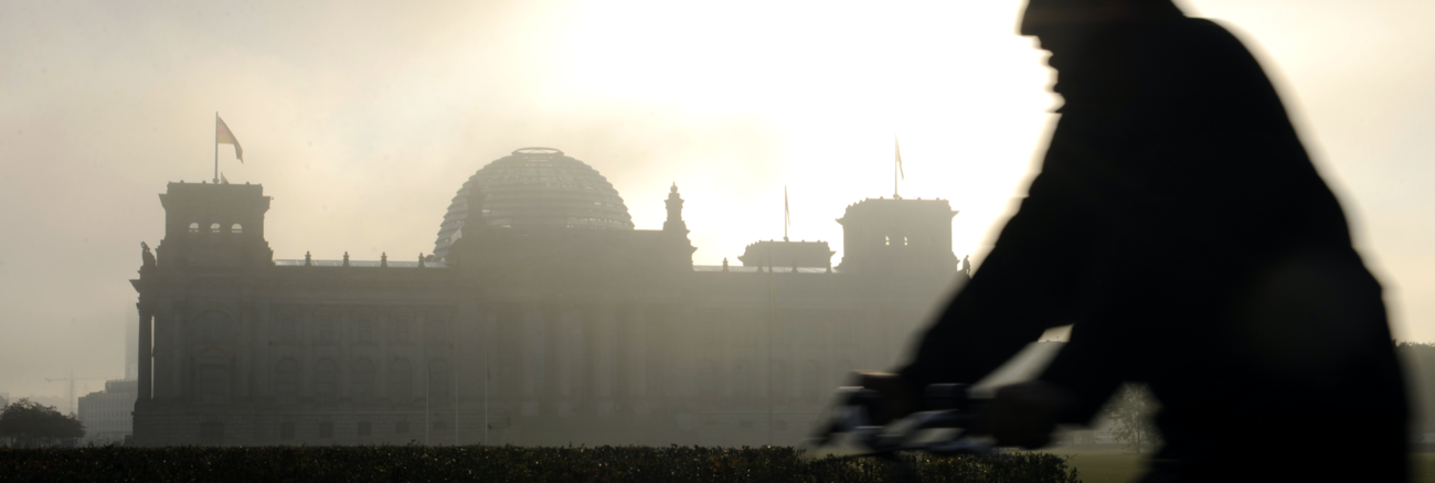 Silhouette eines Fahrradfahrers vor dem Reichstagsgebäude in Morgendunst mit dahinter aufgehender Sonne © picture-alliance/dpa/Rainer Jensen Silhouette eines Fahrradfahrers vor dem Reichstagsgebäude in Morgendunst mit dahinter aufgehender Sonne © picture-alliance/dpa/Rainer Jensen
