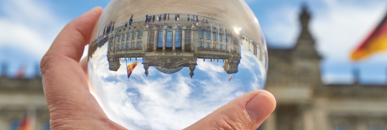 Das Reichstagsgebäude in Berlin durch eine Glaskugel betrachtet auf dem Kopf © iStock/foto-ruhrgebiet