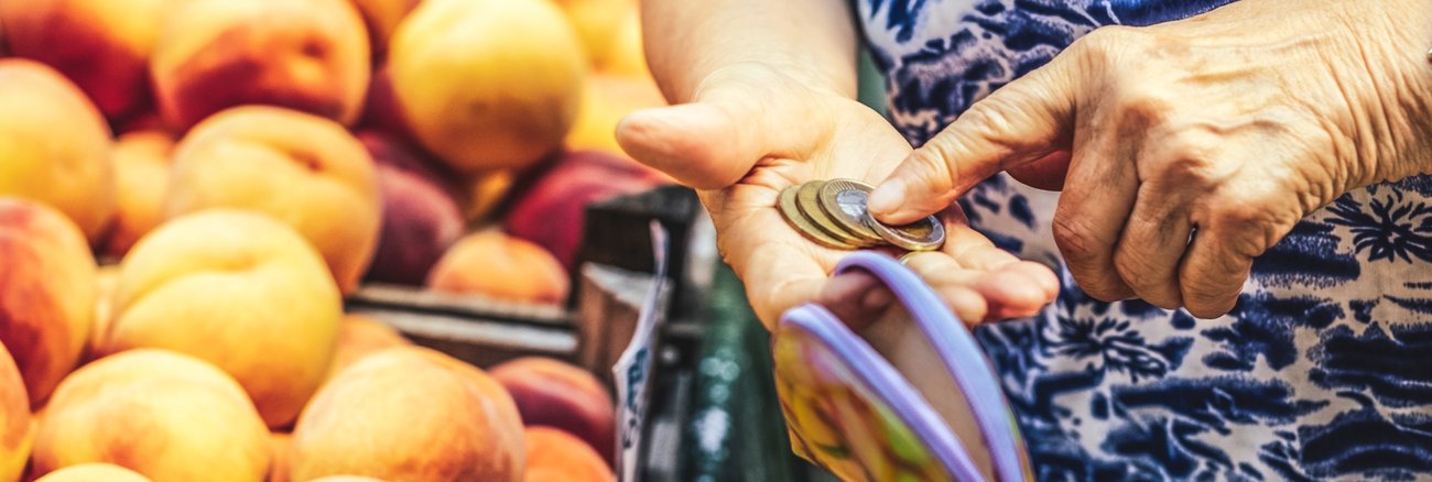 Inflation, Preissteigerungen: Eine ältere Frau im Supermarkt zählt Euro-Münzen in ihrem Portemonnaie © iStock/Eva-Katalin