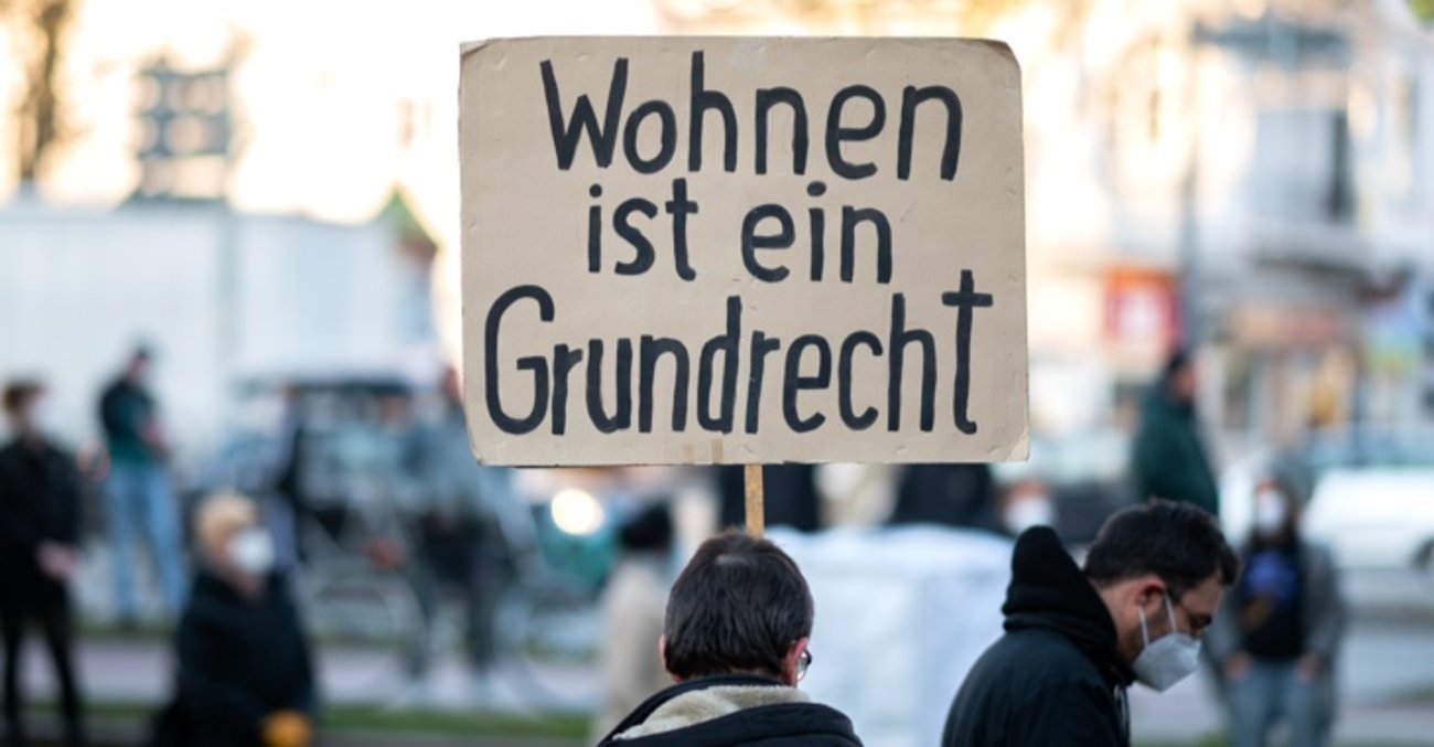 Ein Mann hält ein Schild mit der Aufschrift: Wohnen ist ein Grundrecht © picture alliance/dpa|Daniel Reinhardt