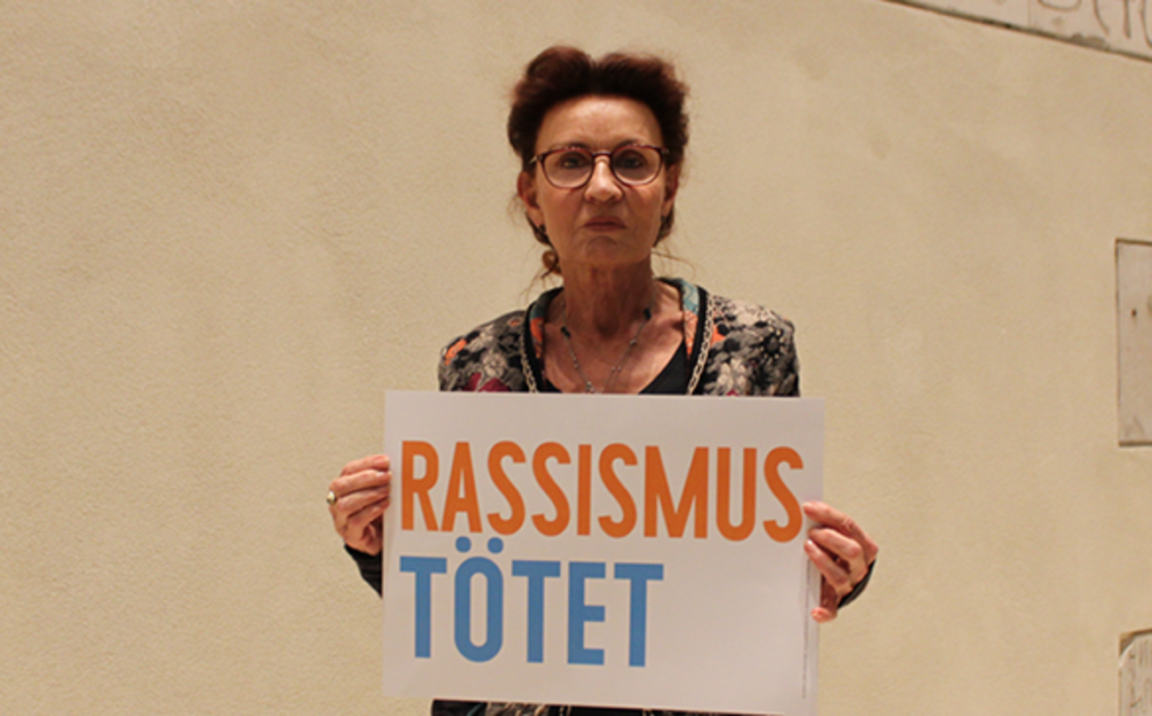 Ulla Jelpke hält ein Schild hoch: Rassismus tötet