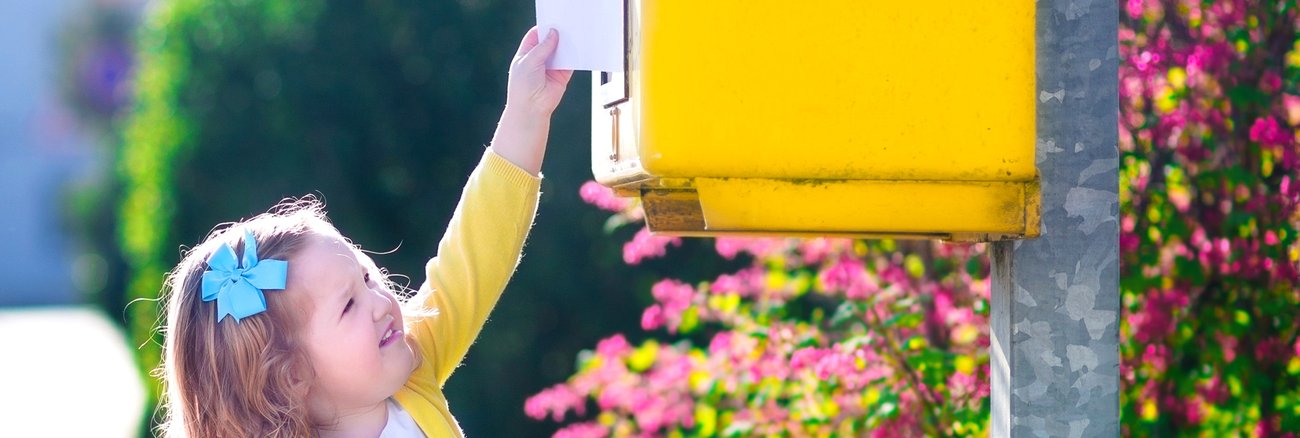 Ein kleines Mädchen steckt mit ausgestrecktem Arm einen Brief in einen Briefkasten © iStock/FamVeld Ein kleines Mädchen steckt mit ausgestrecktem Arm einen Brief in einen Briefkasten © iStock/FamVeld