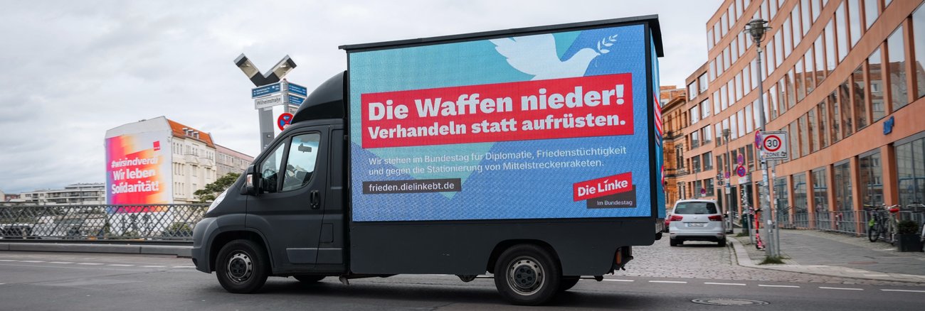 Ein Transporter mit LED-Großfläche mit der Aufschrift: Die Waffen nieder! Verhandeln statt aufrüsten.