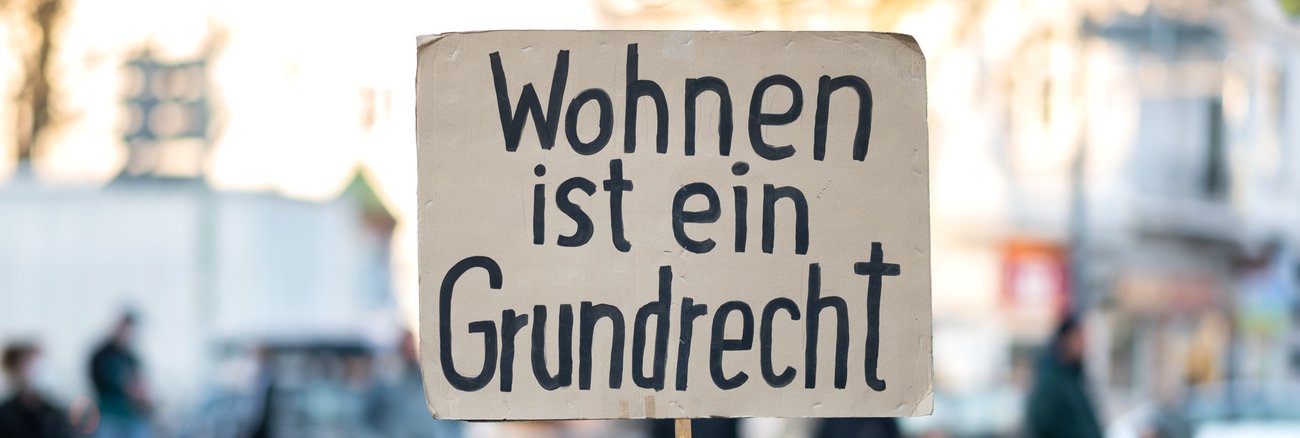 Ein Mann hält ein Schild mit der Aufschrift: Wohnen ist ein Grundrecht © picture alliance/dpa|Daniel Reinhardt