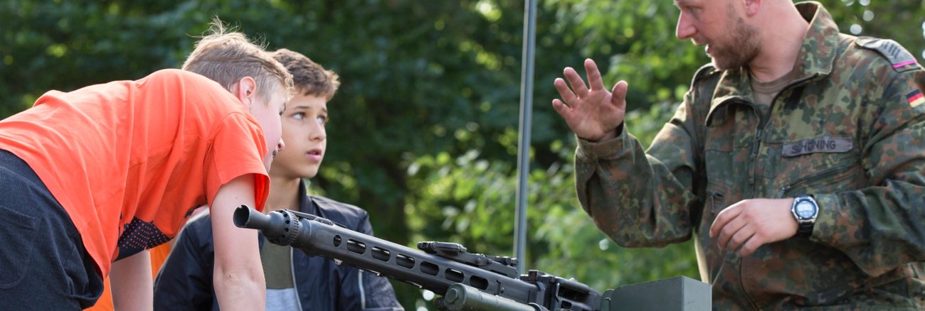 Ein Soldat der Bundeswehr mit zwei Kindern am Maschinengewehr auf dem Geschützturm des Kampfpanzers Leopard II © picture alliance/Ulrich Baumgarten|Ulrich Baumgarten