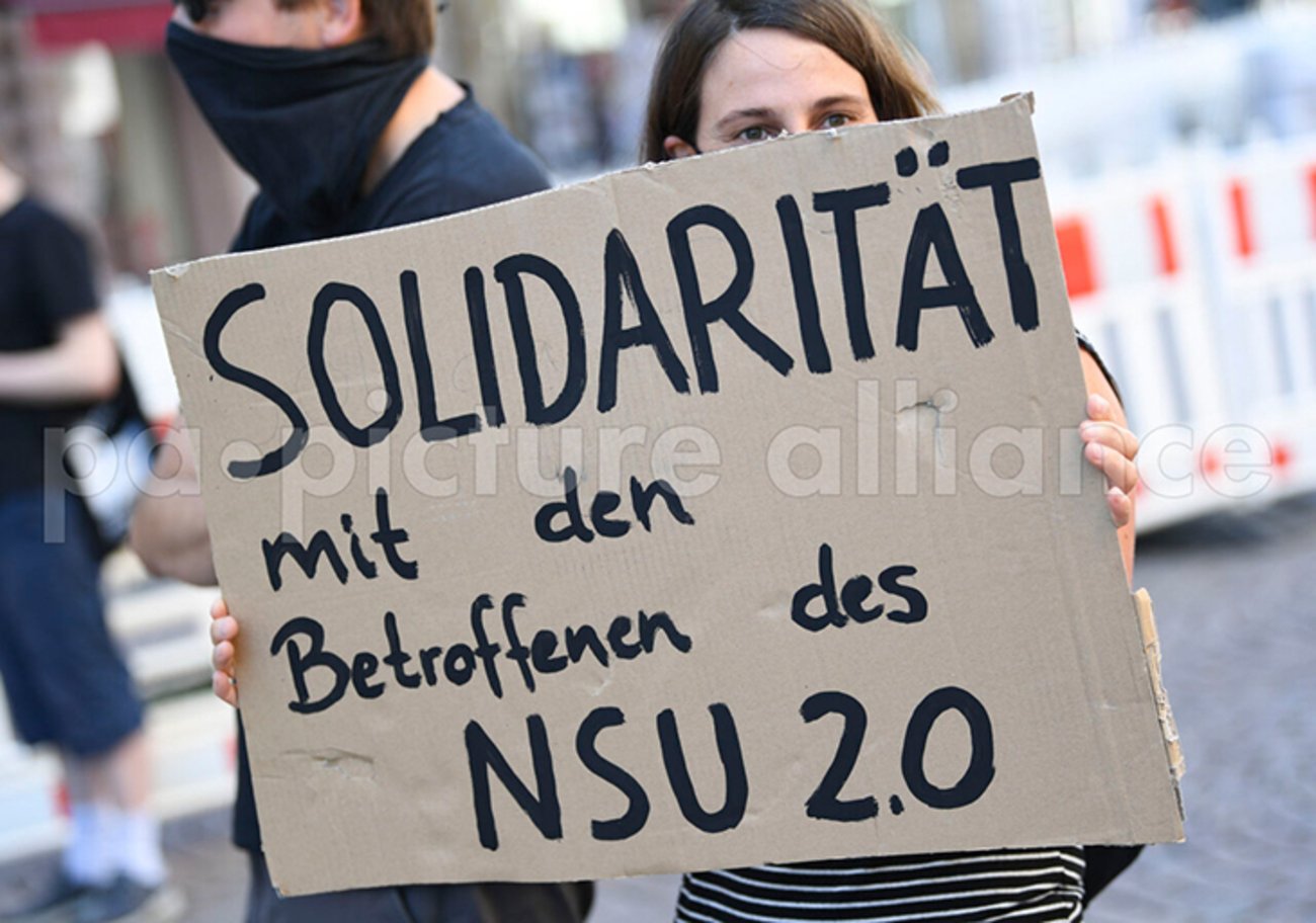 Eine Demonstrantin hält während einer Kundgebung in der Wiesbadener Innenstadt ein Plakat mit der Aufschrift "Solidarität mit den Betroffenen des NSU 2.0". | Foto: © picture alliance/dpa / Arne Dedert Eine Demonstrantin hält während einer Kundgebung in der Wiesbadener Innenstadt ein Plakat mit der Aufschrift "Solidarität mit den Betroffenen des NSU 2.0". | Foto: © picture alliance/dpa / Arne Dedert