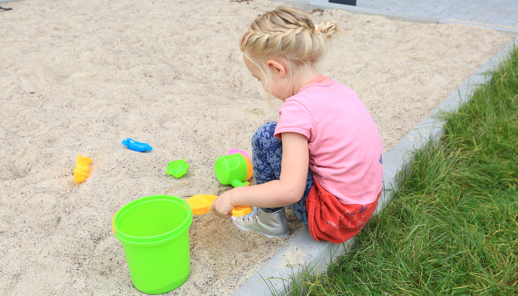 Ein Kind spielt mit buntem Spielzeug im Sandkasten Ein Kind spielt mit buntem Spielzeug im Sandkasten