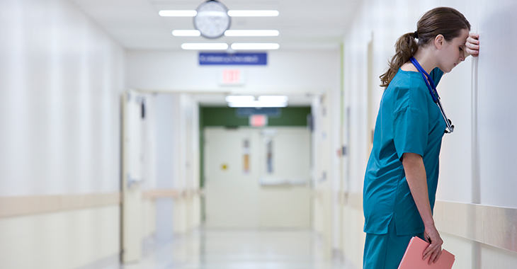 Eine erschöpfte Pflegekraft lehnt an der Wand eines Flurs im Krankenhaus. Foto: © istock.com/FangXiaNuo Eine erschöpfte Pflegekraft lehnt an der Wand eines Flurs im Krankenhaus. Foto: © istock.com/FangXiaNuo