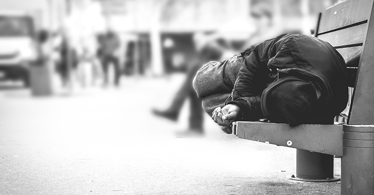 Eine wohnungslose Person liegt auf einer Bank der Straßenmöblierung einer Innenstadt und schläft. Foto: © istock.com/Srdjanns74 Eine wohnungslose Person liegt auf einer Bank der Straßenmöblierung einer Innenstadt und schläft. Foto: © istock.com/Srdjanns74