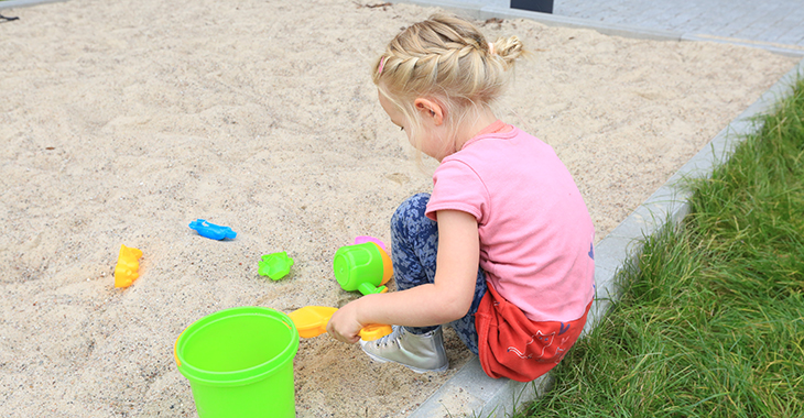 Ein Kind spielt mit buntem Spielzeug im Sandkasten Ein Kind spielt mit buntem Spielzeug im Sandkasten