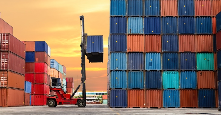 Ein roter Gabelstapler vor einem hohen Containerstapel © iStock/bugphai