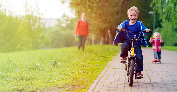 Eine Mutter mit ihrem Sohn auf einem Fahrrad und ihrer Tochter auf einem Tretroller © iStockphoto.com/Nadezhda1906 Eine Mutter mit ihrem Sohn auf einem Fahrrad und ihrer Tochter auf einem Tretroller © iStockphoto.com/Nadezhda1906