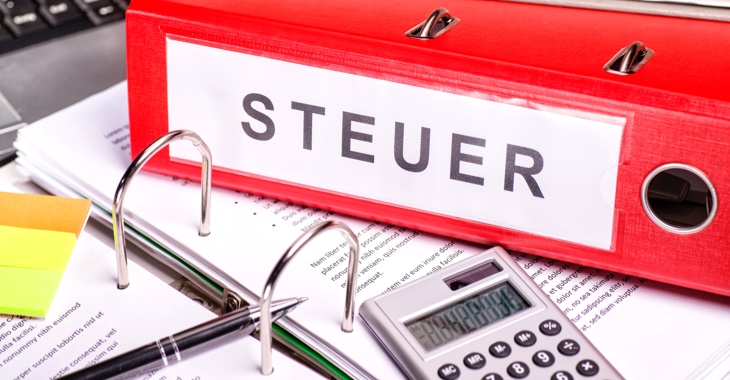 Kugelschreiber, Taschenrechner und ein Aktenordner mit der Aufschrift Steuer © iStock/gopixa