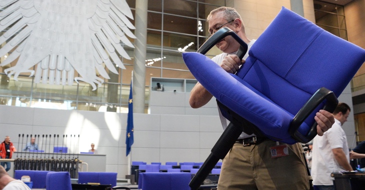 Ein Arbeiter trägt beim Umbau des Plenarsaales des Bundestages einen blau gepolsterten Stuhl © DBT/Achim Melde Ein Arbeiter trägt beim Umbau des Plenarsaales des Bundestages einen blau gepolsterten Stuhl © DBT/Achim Melde