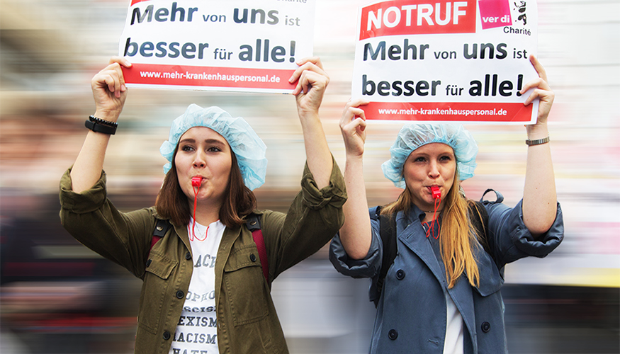 Berliner Pflegekräfte beim Pflegestreik der Charité halten Schilder hoch mit dem Slogan "Mehr von uns ist besser für alle!" Berliner Pflegekräfte beim Pflegestreik der Charité halten Schilder hoch mit dem Slogan "Mehr von uns ist besser für alle!"