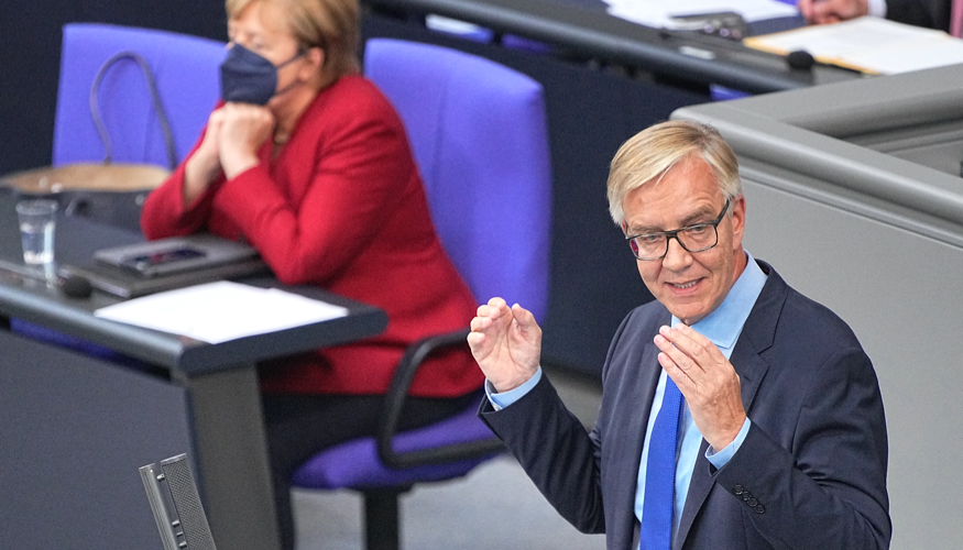 Dietmar Bartsch am Rednerpult des Bundestages, dahinter Kanzlerin Merkel mit Maske und geschlossenen Augen © picture alliance/dpa | Michael Kappeler