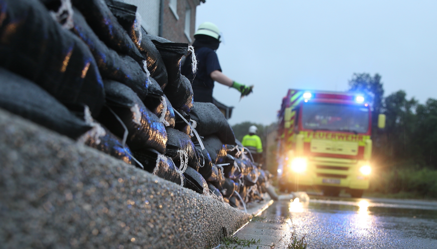 Einsatzkräfte der Feuerwehr errichten am Straßenrand eine Wassersperre aus Sandsäcken © picture alliance/Flashpic/Jens Krick