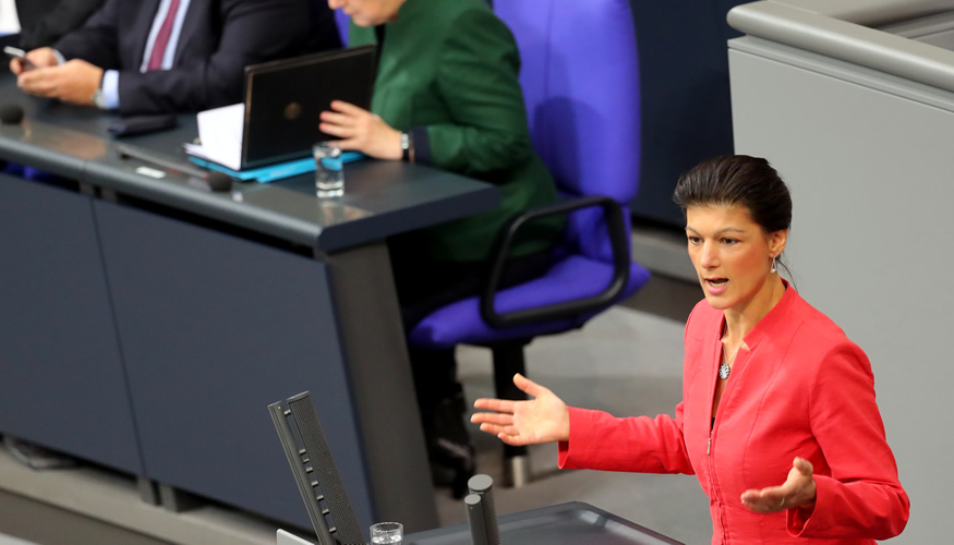 Sahra Wagenknecht am Rednerpult des Bundestages, dahinter Kanzlerin Merkel auf der Reigerungsbank © dpa